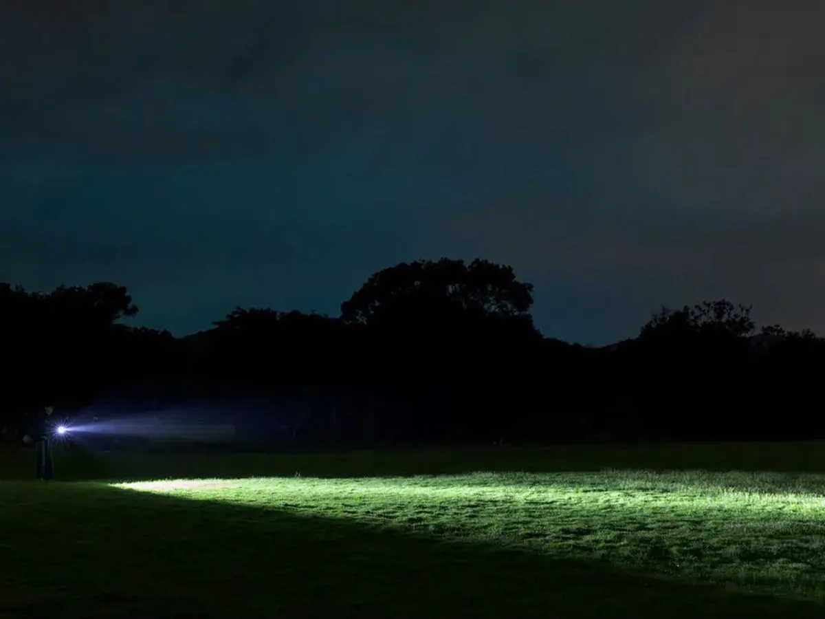 Olight ArkPro Ultra Dual-Beam Field Lighting Olight ArkPro Ultra illuminating a field at night with a wide flood beam and focused spotlight
