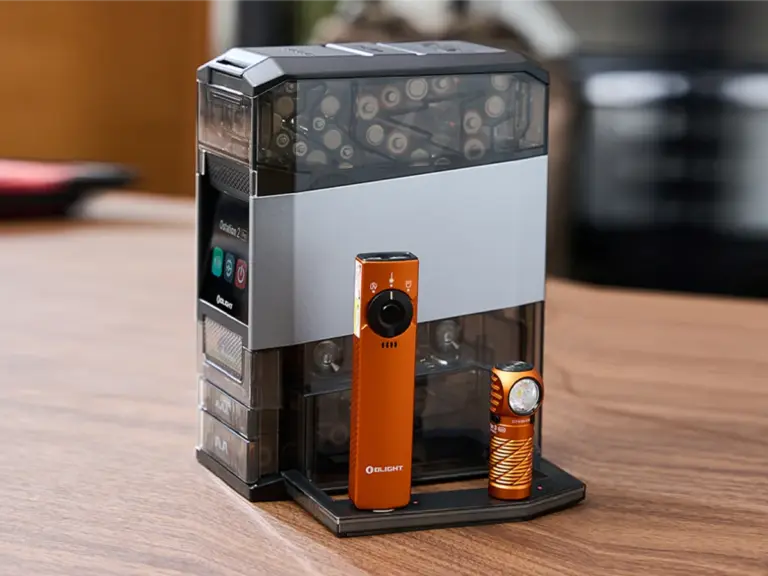 Olight Ostation smart battery station operating beside a desktop monitor