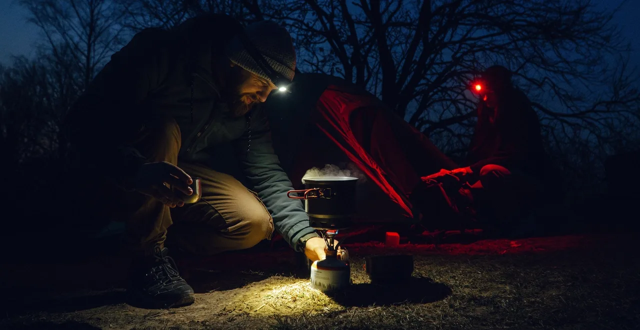 Olight Perun 3 Headlamps at Camp Two people wearing white and red headlamps while cooking at a campsite at night