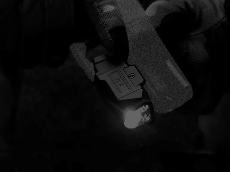 Olight PL X weapon light switched on in a close gloved real-world view
